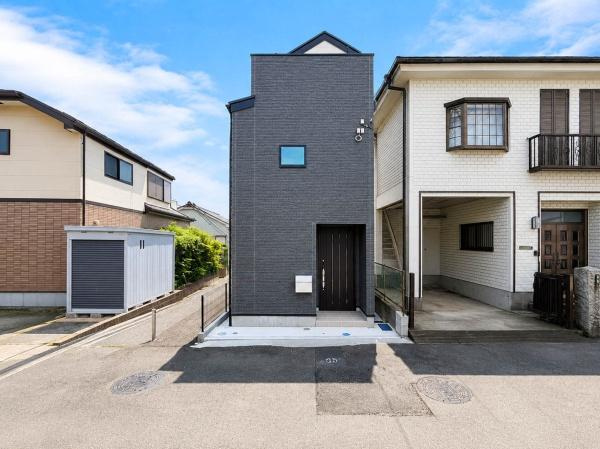 横浜市南区清水ケ丘の新築一戸建の前面道路含む現地写真|正面から見ると、縦のラインを強調したモダンで印象的な外観デザイン。完成済みの新築戸建なので、建物の質感や玄関まわり、周辺環境まで現地でしっかり確認できます。