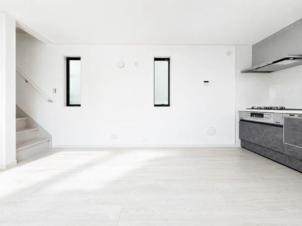 横浜市南区清水ケ丘の新築一戸建の居間・リビング|キッチン横までゆとりが感じられる明るいLDK。白を基調とした内装にグレーのキッチンが映え、家具のテイストを選びにくい空間。階段動線も近く、生活しやすい配置です。窓から自然光も入り、心地よく過ごせます。