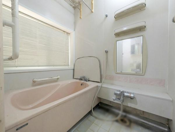 千歳　中古の浴室|窓から自然光が差し込む明るいバスルームです。ゆったりとしたバスタブが設置されています。洗い場には鏡や棚が備わっています。壁には手すりが取り付けられています。落ち着いた色合いが特徴的です。