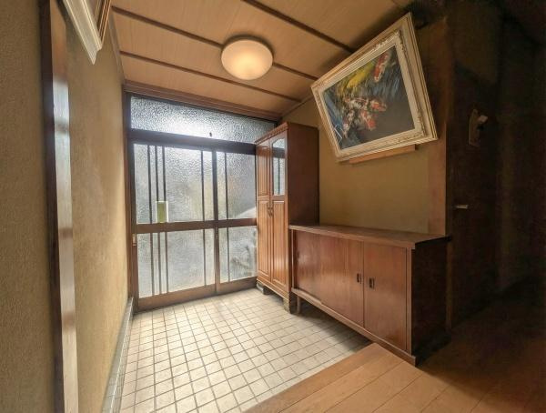 千歳　中古の玄関|玄関は広々としたタイル張りで明るい光が差し込む空間です。収納家具が設置され整理整頓しやすい設計になっています。レトロな雰囲気が感じられ印象的な玄関です。