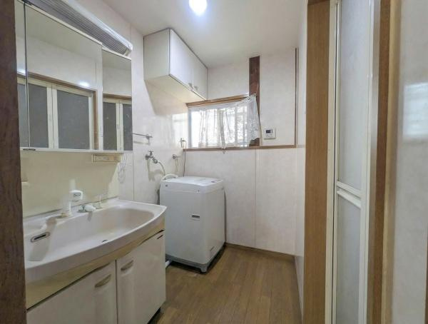 千歳　中古の独立洗面台|明るい空間で洗面台と洗濯機の設置スペースが確保されています。収納棚も備え付けられており日用品の整理がしやすい配置です。木目調の床が清潔感を引き立て毎日の身支度が快適に行えます。