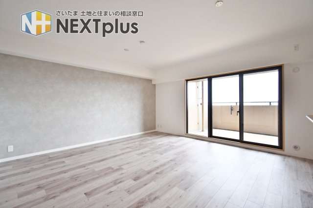 ルネ・グランテラスの居間・リビング|南向きの大きな窓から柔らかな光が差し込む、12.5畳の広々としたリビング。上品なグレーのアクセントクロスが空間を引き締め、洗練された都会的な雰囲気を演出します。家族が自然と集まりたくなる心地よい空間。