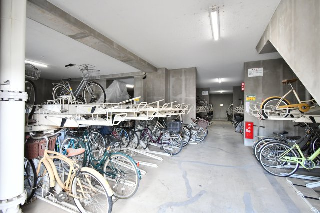 ルネ・グランテラスの駐輪場|屋根付きの駐輪場は、大切な自転車を雨風から守り、劣化を防ぎます。整理整頓された駐輪スペースは、居住者のマナーの良さと管理の徹底を証明。4LDKの広さで家族が増えても、安心して自転車を置ける環境です。