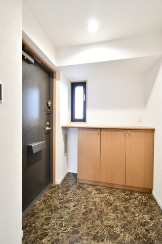 ルネ・グランテラスの玄関|大理石調の床材が住まいの品格を物語る玄関。小窓からの自然光が明るく、圧迫感のない収納棚は飾り棚としても重宝します。リフォーム済みの清潔感あふれる空間が、大切なゲストを優雅にお迎えします。