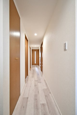 ルネ・グランテラスの玄関|奥行きを感じさせる直線美が美しい廊下。温かみのある木目調の建具とホワイトの壁紙が調和し、住まい全体を明るく演出します。フローリングも一新され、各居室へとスムーズに繋がります。