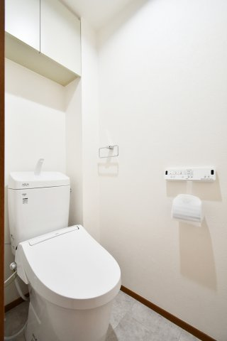 ルネ・グランテラスのトイレ|清潔感あふれる白を基調としたトイレは、温水洗浄便座に交換済み。便利な吊戸棚付きで、生活感を隠してスッキリ収納可能。お手入れしやすい設備が、日々の快適な暮らしを足元から支えます。