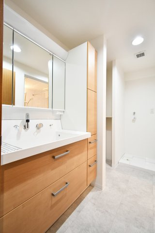 ルネ・グランテラスの独立洗面台|木目調のデザインが温かみを添える、新規交換された洗面化粧台。三面鏡裏の収納に加え、サイドキャビネットも備えた充実の収納力が魅力。広々としたボウルと明るい照明で、忙しい朝の身支度もスムーズに。