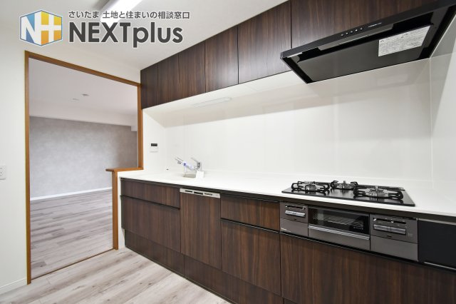 ルネ・グランテラスのキッチン|重厚感ある木目調パネルが美しいキッチンは、食洗機付きのモデルへ一式交換済み。三口コンロや広々とした天板が、日々の料理をより快適に彩ります。リフォームで生まれ変わった贅沢な調理空間。