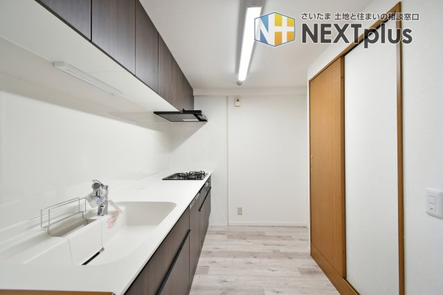 ルネ・グランテラスのキッチン|通路幅にゆとりを持たせた設計で、複数人での作業や大型冷蔵庫の設置もスムーズ。白を基調とした清潔感ある内装に、手入れのしやすいパネルを採用しました。機能性と開放感を両立した、使い勝手の良いキッチンです。