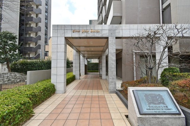 ライオンズヴィアーレ大宮のエントランス|氷川参道の緑に溶け込む、重厚感溢れる意匠。総戸数112戸の大規模レジデンスに相応しい風格が、住まう方のステータスを満たします。植栽が美しく整えられ、管理の良さが一目で伝わる邸宅の顔です。