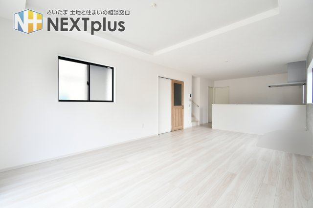 蓮田市馬込11期の居間・リビング|19帖もの広さを誇るLDKは、キッチンから全体が見渡せる安心設計。家族の笑顔を見守りながら料理を楽しめます。折上天井がもたらす開放感と、洗練された内装デザインが日々の暮らしに品格を添える空間です。