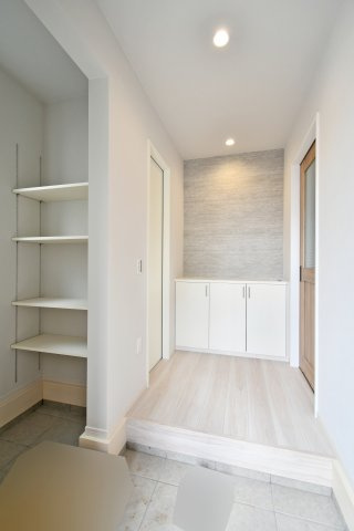 蓮田市馬込11期の玄関|ベビーカーや趣味の道具も丸ごと収まる、大容量の土間収納を完備。可動棚付きで、散らかりがちな玄関を常に美しく保てます。来客時も安心の収納力と、アクセントクロスが洗練された日常を演出します。
