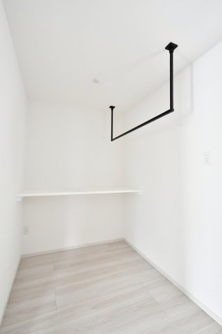 蓮田市馬込11期のランドリースペース|「洗う・干す・畳む」がこの一歩で完結。天候に左右されず、共働き世帯の家事時間を大幅に短縮する専用ランドリールームです。アイアンの物干しバーが、実用性だけでなく空間をモダンに彩る暮らしの相棒です。