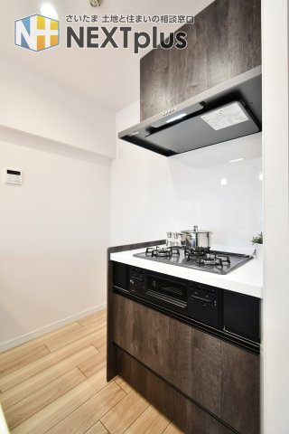 ライオンズマンション大宮浅間町のキッチン|加熱機器を背面に分けたセパレートスタイルを採用。三口コンロでお料理の効率が上がり、油跳ねを気にせずリビング側を清潔に保てます。落ち着いた木目調のデザインが空間を演出します。