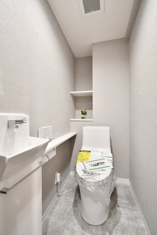 ライオンズマンション大宮浅間町のトイレ|洗浄便座一体型トイレへ新規交換済み。手洗い器を別途設けた贅沢な造りで、背面には小物のディスプレイやストック収納に便利な棚付き。清潔感溢れる空間に仕上げました。