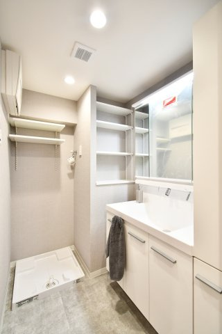 ライオンズマンション大宮浅間町の独立洗面台|機能的な洗面化粧台を新設。洗濯機置場の上部や横に可動棚を設けており、タオルや洗剤もスッキリ収納可能。三面鏡裏の収納など、忙しい朝の身支度をスムーズにする工夫が満載です。