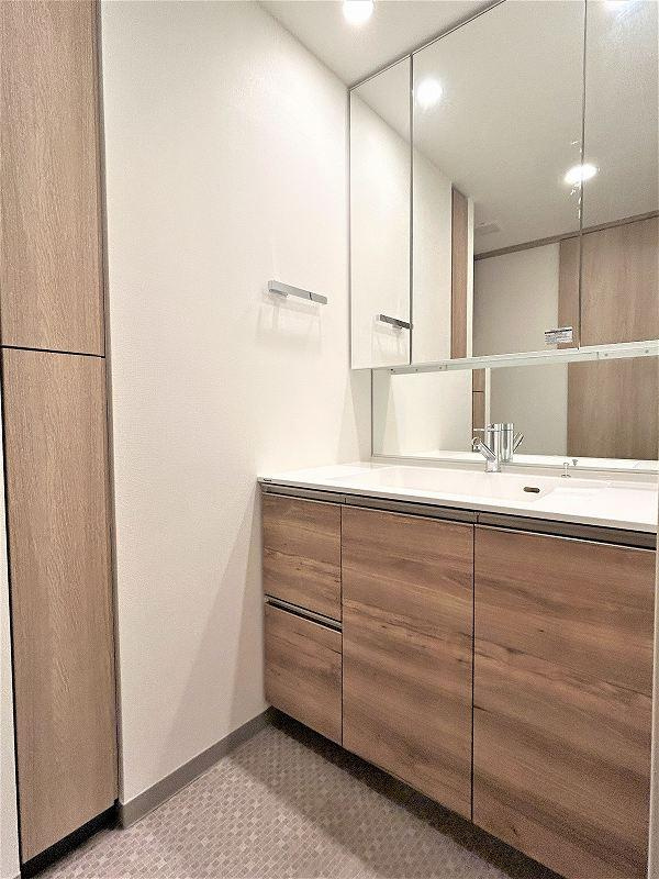 カサーレ小平の洗面所|三面鏡の下にはチャイルドミラーを設置し、お子様でも見やすくしております。また、洗面カウンターとボウルは継ぎ目のない一体タイプで、有機ガラス系の新素材が汚れをはじき、お手入れも簡単です。