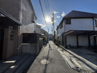 【前面道路含む現地写真】 | 物件に隣接する前面道路は、落ち着いた住宅街へと続く静かな環境です。周囲に高い建物が少ないため空が広く感じられ、暖かな陽光が差し込む心地よいアプローチが、住まう人を優しく迎え入れてくれます。