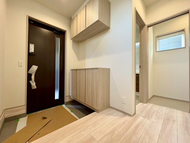 「続き間で23帖超えの大空間」香美市土佐山田町東本町2号棟　新築一戸建ての玄関|木目調のシューズボックスが目を惹く玄関。上下に分かれた収納で、家族の靴もたっぷり収まります。洗面室への動線も良く、帰宅後の手洗いもスムーズ。