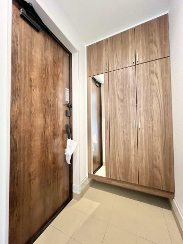 磐田市見付　2期　1号棟の玄関|木目調で統一された温かみのある玄関！大容量シューズボックスと姿見付きで、収納力と使い勝手を兼ね備えています。