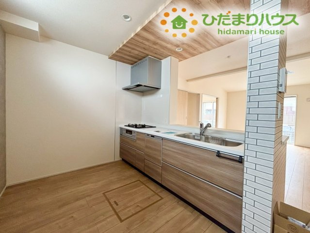 行田市谷郷　新築一戸建て　ブルーミングガーデン　01のキッチン|お料理中も家族との会話が弾む、お洒落な対面式のシステムキッチンです！木目調の下がり天井がアクセントになっており、カフェのような気分で毎日の料理を楽しめます♪収納も豊富で調理器具がサッと片付きます！
