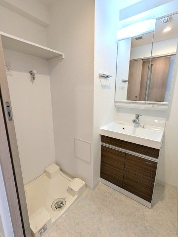 グランカーサ上野松が谷の洗面所|トイレと独立した洗面脱衣室、2面鏡付・ハンドシャワー付洗面台、洗濯機置場は排水口のお手入れしやすい様に手前中央に配置し、足高の防水パンです