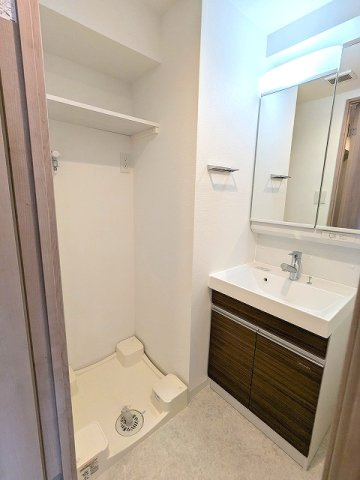 グランカーサ上野松が谷の洗面所|トイレと独立した洗面脱衣室、2面鏡付・ハンドシャワー付洗面台、洗濯機置場は排水口のお手入れしやすい様に手前中央に配置し、足高の防水パンです