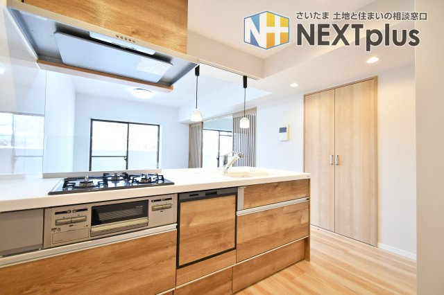 ファミール大宮宮原壱番館のキッチン|視界を遮る吊戸棚がない開放的なデザイン。料理をしながらリビングの様子を見渡せます。食洗機や浄水器一体型水栓など設備も充実。木目調の温かみと機能美が、毎日の家事を豊かな時間へと変えてくれます。