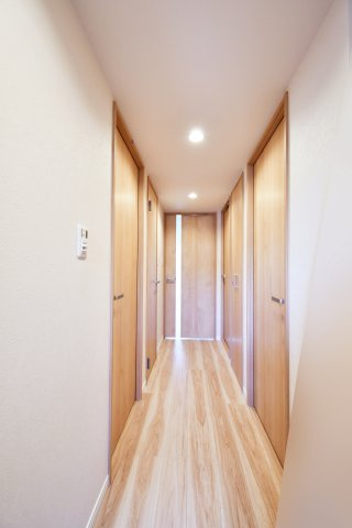 ファミール大宮宮原壱番館の玄関|リビングへと続く廊下は、美しい木目のフローリングが奥行きを強調。各居室への扉も同トーンで統一され、空間全体に洗練された一体感を生んでいます。細部までこだわり抜いた住まいを、現地でご体感ください。