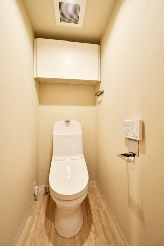 ファミール大宮宮原壱番館のトイレ|白を基調とした、衛生的で心地よいレストルーム。上部にはストック品を隠して収納できる便利な吊戸棚を設置しました。毎日使う場所だからこそ、シンプルで掃除のしやすい設えにこだわっています。