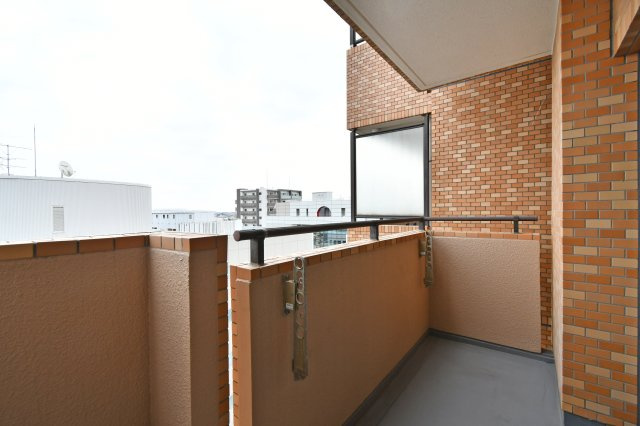 ライオンズプラザ大宮のバルコニー|レンガ調の腰壁で視線をほどよく遮るバルコニー。物干し金具付きで洗濯物を干しやすく、奥行きも確保。外の空気を感じながら小休憩にも。手すりがあり、出入りの際も足元を確認しやすい配置になっています。
