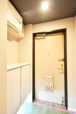 ライオンズプラザ大宮の玄関|白基調の玄関は上部まで使えるシューズボックス付き。カウンターには鍵や小物を置け、土間にゆとりがあるためベビーカー等も出し入れしやすい玄関周りです。身支度の動線が整い、壁面も活用しやすいです。