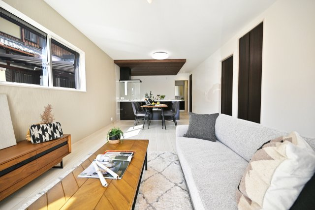 伊丹市寺本1丁目新築一戸建て│3SLDK+並列駐車2台可の居間・リビング|リビング側からキッチンに向かって撮影した写真です。家具やテーブルが配置しやすい形状のリビングは実用的です。