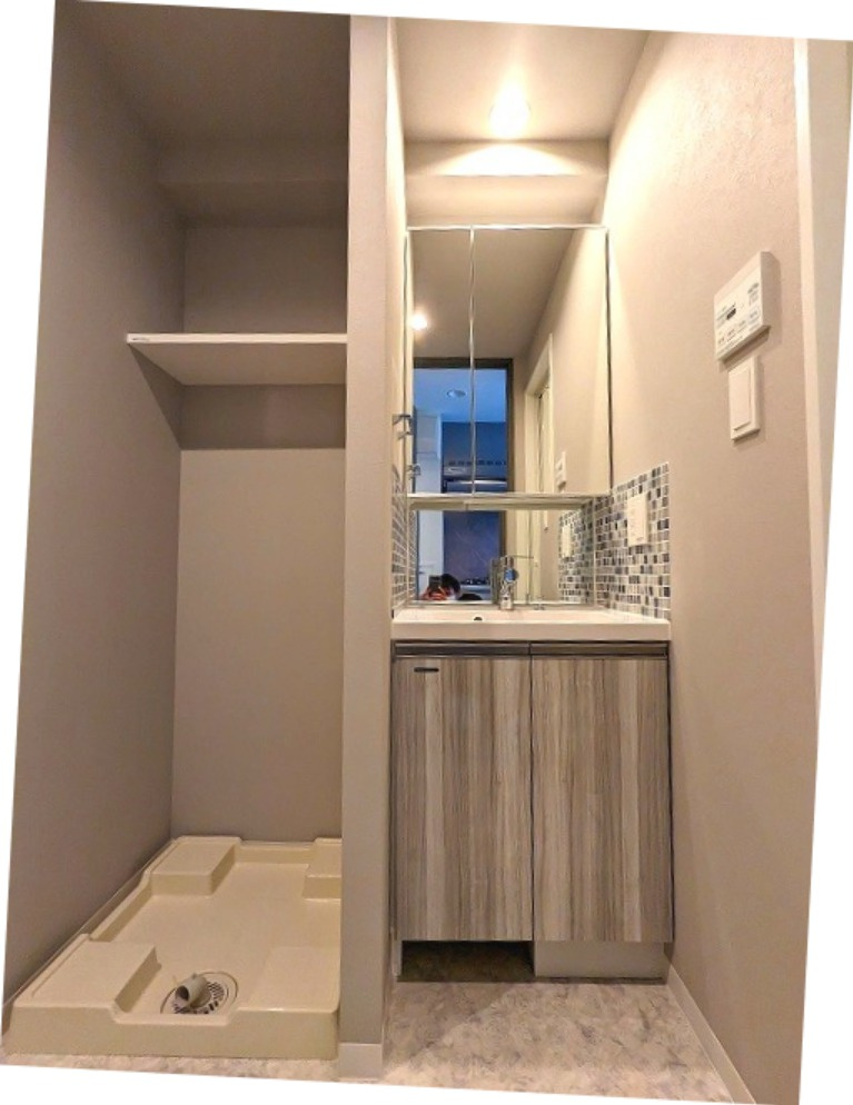 GRAND CONCIERGE浅草橋の洗面所|洗面台の下にヘルスメーターストックスペースあります。洗濯機置場はお手入れしやすい様に足高の防水パンで、排水溝を手前の中央に配置しています