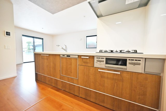 テラシエ尼崎市久々知1丁目新築一戸建て｜4LDK＋駐車1台可のキッチン|キッチン奥から撮影した写真です。木目調の色合いのキッチンは周囲の床や建具にもマッチして空間の一体感を生み出しています。