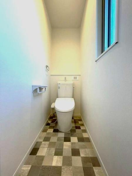 HT挾間のトイレ|モダンなチェック柄のフロアが特徴的なトイレです。明るい窓から自然光が差し込み清潔感のある空間です。壁の色使いがシンプルですっきりとした印象を与えます。