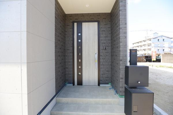 P-TELAS牧１丁目2号地の玄関|シンプルながらもモダンなデザインの玄関です。段差も低めでアクセスしやすい造りとなっています。ダークトーンの外壁と調和した落ち着いた印象です。