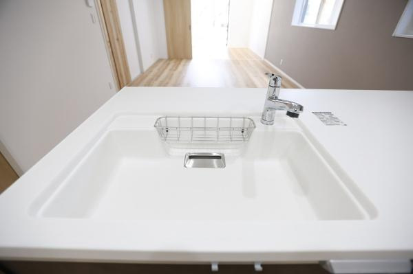 P-TELAS牧１丁目2号地のキッチン|清潔感のある明るいキッチンシンクが特徴です。広々としたカウンターで作業がしやすい設計です。シンプルなデザインで室内の雰囲気にも調和しています。窓からの採光もあり明るい印象です。