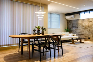 【居間・リビング】 | リビングの壁面には表情豊かな大判タイルを採用。間接照明の柔らかな光が壁の凹凸を際立たせ、落ち着いた夜の時間を彩ります。お気に入りのソファに身を委ね、ゆったりと映画鑑賞や読書を楽しむ贅沢な日常を。