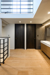 【内装】 | 黒のアイアン手すりがアクセントとなり、空間を引き締めます。吹き抜け越しに上下階の繋がりを感じられる設計で、ご家族の気配を程よく共有。木の質感が心地よい廊下は、歩くたびに住まいの品質を実感できます。