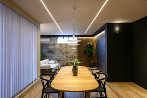 【居間・リビング】 | 質感の異なる壁材を組み合わせた、デザイン性の高い内装。窓の外にはバルコニーが広がり、柔らかな光が差し込みます。30畳超の広さを活かして、大型の家具もゆとりを持って配置できる自由度の高さが魅力です。