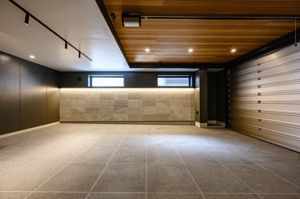 【駐車場】 | 奥行きのある車庫内には、サイドに質感豊かな石積み風の壁面と間接照明を配置。複数台の駐車も相談可能なゆとりがあり、夜間の荷物出し入れも明るくスムーズです。住まいと一体化した動線で、移動も快適。