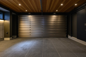 【駐車場】 | 大切なお車を雨風から守る、シャッター付きの屋内車庫です。天井には温もりある木目調のパネルをあしらい、愛車を眺める時間も贅沢に。照明付きの広々とした空間は、趣味を楽しむガレージとしても重宝します。