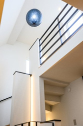 【内装】 | 高い天井から柔らかな光が降り注ぐ、開放感あふれる吹き抜け。スタイリッシュなペンダントライトが、家族の集う空間を優しく照らします。毎日の暮らしの中で、ゆとりと開放感を味わえる贅沢な設計です。