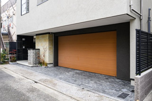 【前面道路含む現地写真】 | 道路との高低差が少なく、スムーズに車庫入れができるアプローチ。電動シャッターを採用しているため、車内からリモコン一つで開閉が可能です。忙しい朝の出発も、帰宅時の入庫もストレスなくスマートに。