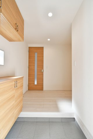上尾市原市全1棟　1号棟の玄関|木の温もりに包まれる明るい玄関。大型の下駄箱完備でスッキリ片付き、スマートな電子キーが日々の帰宅を快適にサポートします 。平屋ならではの開放的な動線が、家族を優しく迎え入れる住まいの顔です。