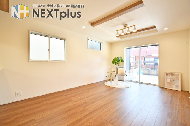 北足立郡伊奈町中央4丁目全2棟　2号棟の居間・リビング|南道路に面した大開口の窓に加え、壁面上部にも複数のスリット窓を配置。溢れる陽光が折上天井まで届き、一日中明るいLDKを実現しました。視線を遮りつつ光を取り込む設計で、プライバシーと開放感を両立します。