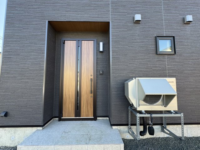 釧路市愛国東1丁目Kospaモデル▽家事動線と収納力が自慢の高性能な家の外観|シックな外壁に映える木目の温もり。暮らしを彩る玄関デザイン。