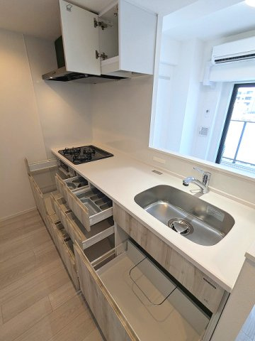 エスレジデンス浅草clarityのキッチン|グリル付ガス3口システムカウンターキッチン、奥の物も取り出しやすいスライド収納、瀟洒でお手入れ楽なガラストップコンロです、広々のシンクです