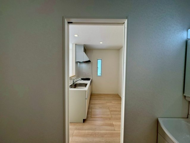 クレイドルガーデン南城市佐敷佐敷 第1・２号棟のキッチン|洗面室とキッチンが行き来しやすい、水回り集中設計／廊下側にも扉がある2ドア仕様の洗面室